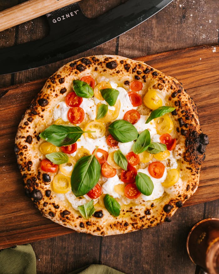 Top view of a delicious Neapolitan pizza with vibrant cherry tomatoes and basil leaves.